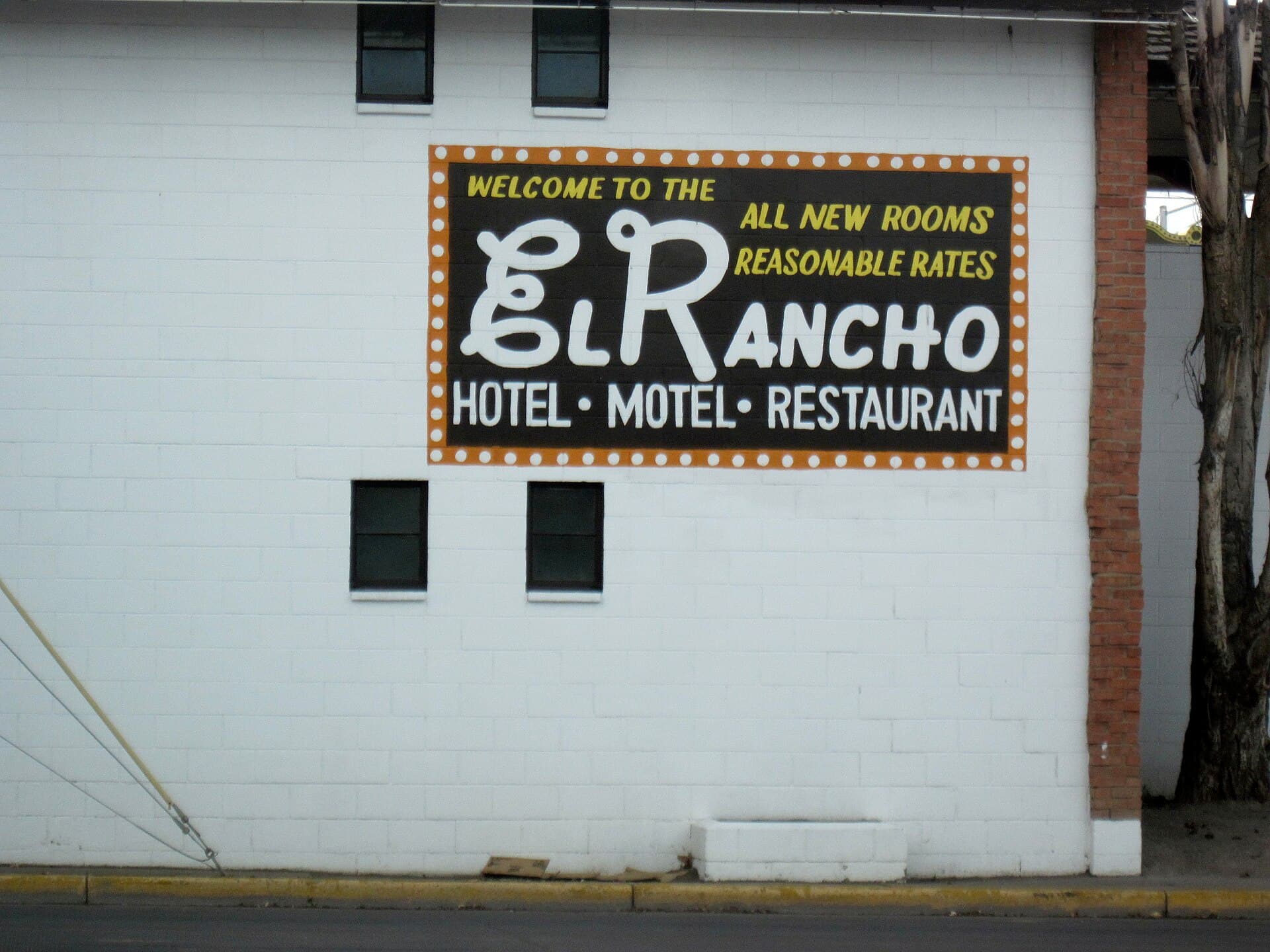 A hand-painted sign for the El Rancho motel on a whitewashed wall